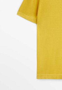 Short-sleeve yellow t-shirt made of soft fabric, displaying a clean cut, prominent stitching, and a smooth texture with folded hem.
