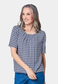 Marineblauw top met korte mouwen, voorzien van een geometrisch ruitpatroon in het wit en een geraffineerde halslijn. Gekozen om te dragen met blauwe spijkerbroeken.