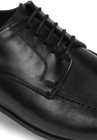 Zwarte leren schoen met een gladde afwerking, voorzien van zes veterogen, subtiele stiksels en een ronde neus.