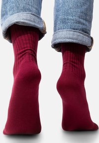 Bordowe skarpetki z bawełny, o prążkowanej fakturze i średniej długości, w połączeniu z dżinsami niebieskimi z podwiniętymi nogawkami.