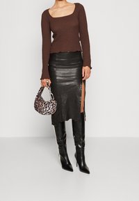 Brun texturerad långärmad topp, svart läder midi kjol med sid slit, knähöga svarta stilettboots och en leopardmönstrad handväska.