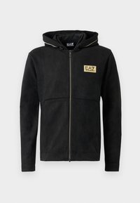 Black zip-up hoodie made of soft material, featuring a gold logo on the chest, contrasting zipper, and a drawstring hood.