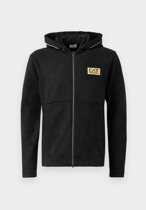 Black zip-up hoodie made of soft material, featuring a gold logo on the chest, contrasting zipper, and a drawstring hood.