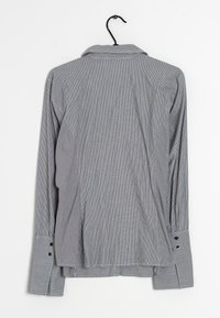 Chemise à manches longues en motif rayé bleu et blanc, avec col, poignets boutonnés et ourlet droit. Le tissu semble léger.