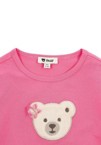T-shirt rosa a maniche corte con applicazione di un volto di orso bianco in peluche e un piccolo fiore rosa decorativo sull'orecchio sinistro. Girocollo.