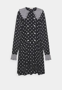 Robe noire à manches longues avec des pois blancs, dotée d'un col et de poignets en vichy texturé, et d'accents de boutons en perle. Jupe plissée.