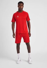 Rode atletische t-shirt en korte broek set gemaakt van ademend materiaal, met korte mouwen en een ronde hals. Inclusief logodetail op de borst.