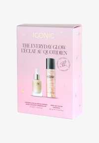 Due bottiglie cosmetiche in una scatola rosa. A sinistra: bottiglia in vetro con pipetta e tappo argentato, liquido trasparente. A destra: contenitore trasparente con tappo nero, liquido luccicante.