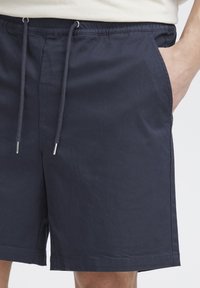 Tengerészkék pamut rövidnadrág gumis derékrésszel, állítható húzózsinórral és oldalzsebekkel. Egyszerű dizájn egyenes szabással.