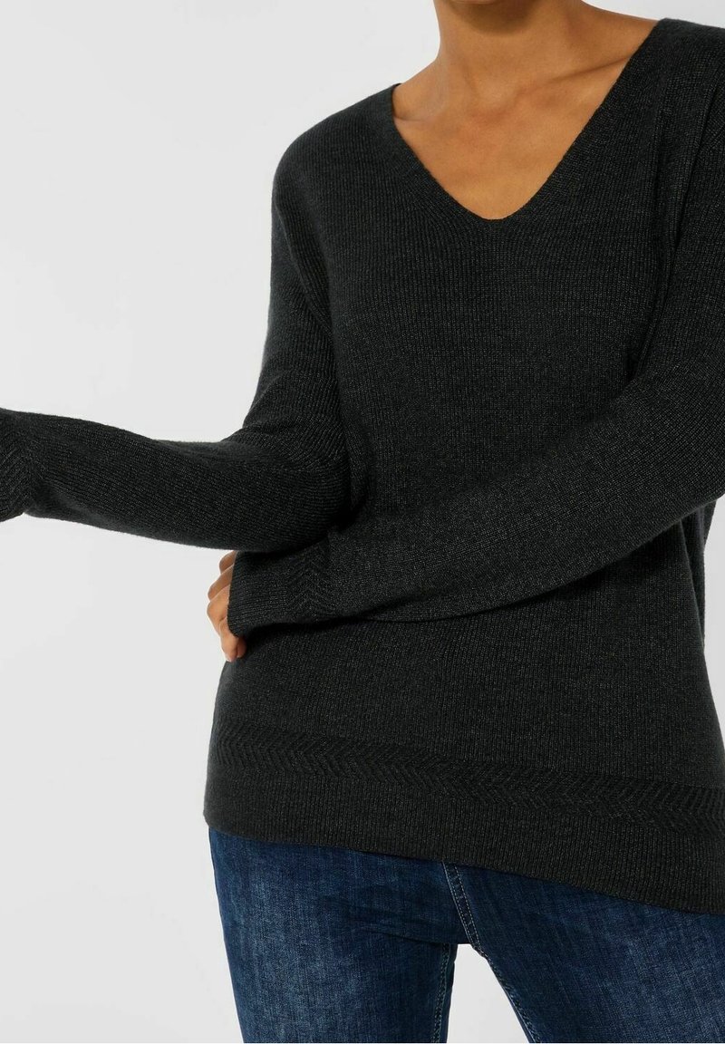 Pull à col V côtelé gris foncé avec des manches longues et un ourlet texturé. Fabriqué en matériau doux, conçu pour un ajustement décontracté.