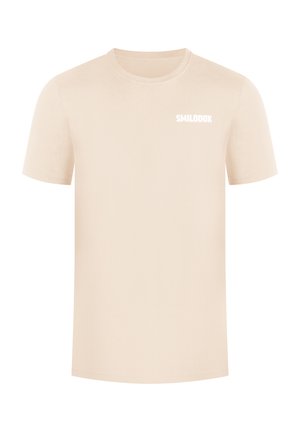 Beige katoenen t-shirt met korte mouwen, ronde halslijn en een klein wit logo met de tekst "SMILODOX" op de voorkant. Gladde textuur, casual ontwerp.
