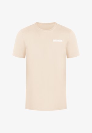 Beige katoenen t-shirt met korte mouwen, ronde halslijn en een klein wit logo met de tekst "SMILODOX" op de voorkant. Gladde textuur, casual ontwerp.