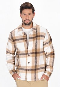 Beige och vit rutig skjorta med bruna och grå detaljer, med knäppning fram, långa ärmar och ett mjukt, texturerat tyg.