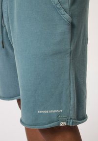 Blauwe katoenen shorts met een zachte textuur, voorzien van zijzakken, een trekkoord in de taille en een logo-label aan de zoom in contrasterend wit.