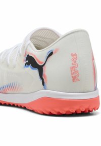 Zapatilla deportiva blanca con acabado texturizado, que presenta un logo de Puma negro, un acento rosa en la suela y patrones de degradado coloridos en la parte superior.