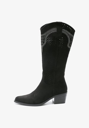 Czarne zamszowe wysokie kozaki do kolan z perforowanym wzorem i dekoracyjnymi akcentami. Mają lekko spiczasty czubek oraz niski słupkowy obcas.