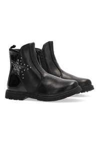 Botas de tobillo de imitación de cuero negro con cremallera lateral, que presentan un diseño de estrella adornado con rhinestones y una suela de goma texturizada.