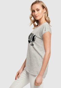 Grå t-shirt lavet af blødt stof, med et sort grafisk design med en stregkode og dyremotiv på forsiden. Korte ærmer og afslappet pasform.