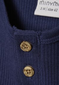 Navy ribstof kledingstuk met een ronde halslijn, voorzien van twee beige-bruin knopen met een textuur. Label geeft maat 3M, 62 aan.