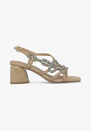 Beige heeled sandal featuring a wide strap with multicolored rhinestone embellishments and a chunky heel. Buckle strap closure at ankle.