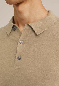 Polo bej dintr-un material texturat, cu un guler clasic și trei nasturi gri pe plastron, evidențiind un design casual.