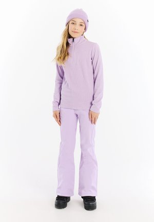 Lichtpaarse pullover met een ritskraag, gecombineerd met lichtlavendelkleurige broek. Beide kledingstukken hebben een geribbelde textuur. Zwarte schoenen maken de outfit compleet.