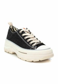 Zapatilla textil negra con una suela blanca gruesa, cordones crema y un forro interior a rayas. Incluye herrajes metálicos en los ojales.