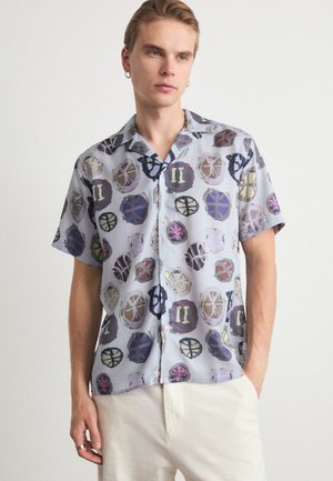 Short-sleeve, collared shirt in light blue with a colorful abstract print of circles and symbols. Lightweight fabric with a smooth texture.