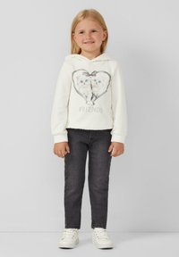 Witte hoodie met twee kittens in een hartontwerp en de tekst "VRIENDEN" eronder. Grijze spijkerbroek en witte sneakers maken de outfit compleet.