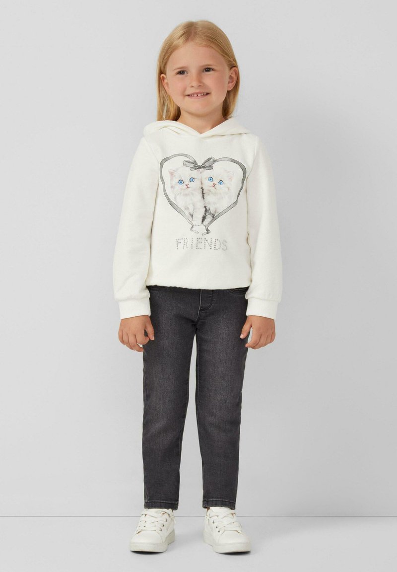 Witte hoodie met twee kittens in een hartontwerp en de tekst "VRIENDEN" eronder. Grijze spijkerbroek en witte sneakers maken de outfit compleet.