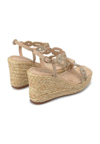 Beige Keil-Sandaletten mit aufwändigem Durchbruchsdesign der Riemen, geschmückt mit Strasssteinen. Strukturiert eingewickelter Jute-Absatz, mit gepolsterter Innensohle.