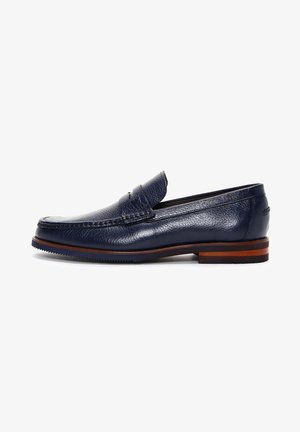 Mocassins en cuir bleu marine avec une finition texturée, une forme arrondie et une semelle brune contrastante. Style à enfiler avec des détails de couture subtils.