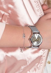 Zilverkleurig horloge met glinsterende band, gedurfde "LOVE"-ontwerp op de wijzerplaat en een delicate zilveren armband met een kleine bedel.