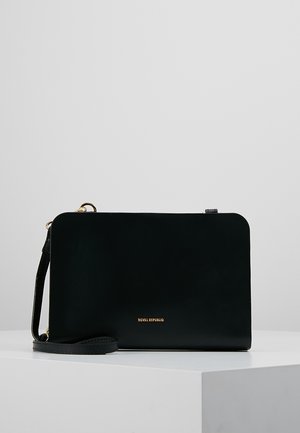 Bolso bandolera rectangular de cuero negro con logo dorado "Royal Republiq" y correa de hombro desmontable sobre pedestal blanco.