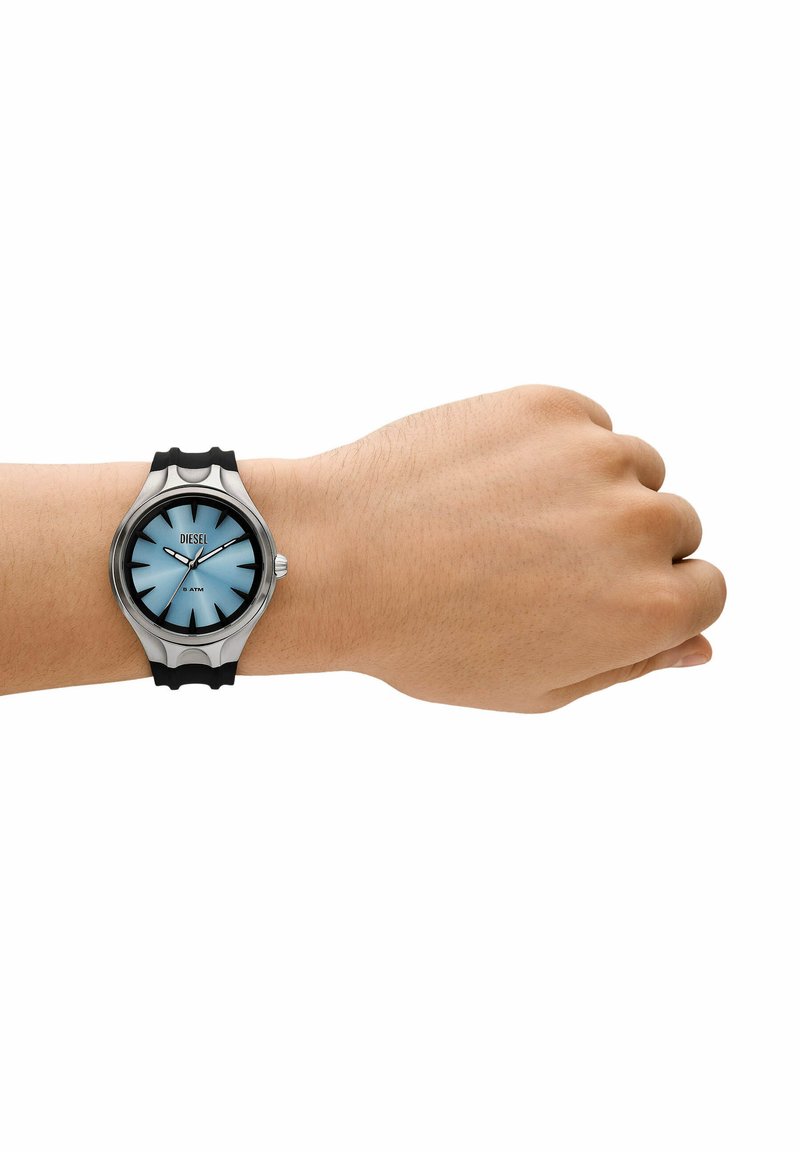 Polso con un orologio Diesel con quadrante blu, indici delle ore neri, cassa in argento e cinturino nero, che mostra l'ora 10:10.
