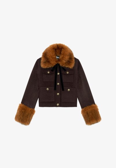 Chaqueta marrón corta con un cuello y mangas de piel sintética, botones dorados, dos bolsillos frontales y un detalle de lazo de terciopelo en el escote.