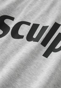 Tessuto grigio dalla texture morbida, con una scritta nera audace che recita "sculp" sulla superficie. Il design è semplice e moderno.