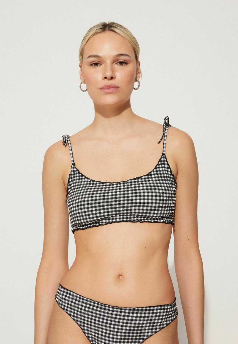Zwart-wit geruite bikini-set met een cropped top met rimpelranden en verstelbare stropdassen, gecombineerd met bijpassende bikini onderbroek.