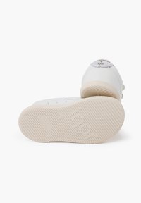 Zapatillas de goma blancas con punta redondeada, suela texturizada y acentos en gris claro. Marca visible en el talón y la suela.