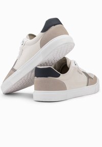 Jasne sneakersy wykonane z połączenia gładkich i zamszowych materiałów. Posiadają białą gumową podeszwę oraz ciemne akcenty na pięcie.