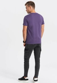 Lilla bomulds T-shirt, korte ærmer, rund halsudskæring, parret med sorte cargo-bukser, sidelommer, tætsiddende design, båret med sorte og hvide sneakers.