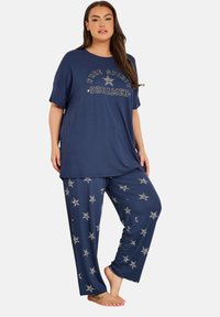 Marinblå pyjamasset med en kortärmad skjorta med texten "Free Spirit Dreamer" och stjärnmönstrade byxor med elastisk midja; mjukt tyg.