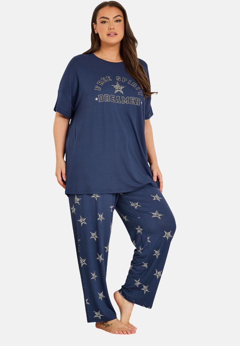 Marinblå pyjamasset med en kortärmad skjorta med texten "Free Spirit Dreamer" och stjärnmönstrade byxor med elastisk midja; mjukt tyg.