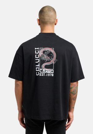 Sort bomulds T-shirt med et stort rødt og hvidt dragegrafik på bagsiden, med teksten "Colucci", "Carlo" og "Est. 1978".
