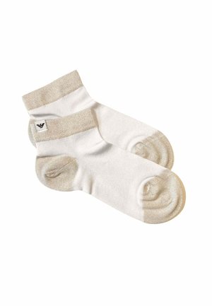 Coppia di calzini bianchi alla caviglia con polsini, talloni e punte beige, caratterizzati da un piccolo logo nero sul polsino laterale.