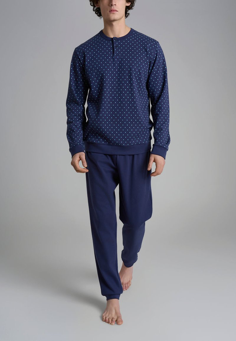 Set di abbigliamento da casa blu navy; felpa con pois blu chiaro e colletto a bottoni, abbinata a pantaloni blu navy. Indossato da un modello.