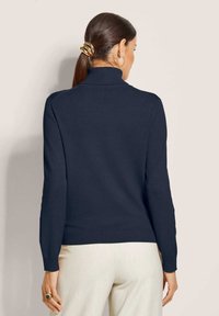 Marinefarbener Rollkragenpullover mit gerippten Bündchen und Saum, aus einem glatten Strickstoff gefertigt. Hat lange Ärmel und eine taillierte Silhouette.