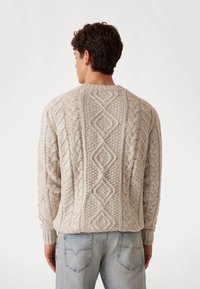 Hellbeige gestrickter Pullover mit strukturierten Zopfmustern und Rautenformen. Rippbündchen und -saum verbessern die Passform und das Detail.