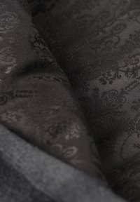 Tissu noir mettant en valeur un motif floral texturé subtil, avec des nuances de noir variées offrant une profondeur et une nuance visuelle.