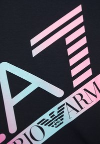 Černá textilie s velkým grafickým designem, kde je v gradientních pastelových barvách a pruhovaných akcentu umístěno "A7", včetně prvků loga a textu.